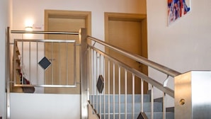 A staircase with a metal railing, wooden ceiling beams, and a wall-mounted abstract painting. - Bella Monte by Interhome (Pettneu am Arlberg)