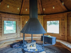 A wood-burning stove in a cabin with wooden walls and windows. - Vuorimaja by Interhome (Ristiina)