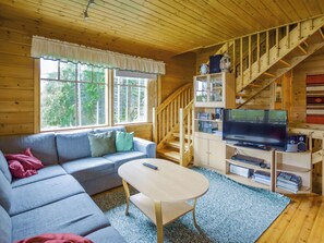 A cozy cabin interior with a sofa, a television, and a staircase. - Vuorimaja by Interhome (Ristiina)