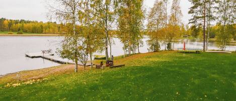Un parc au bord du lac, avec une pelouse, des arbres, une jetée et un banc.
