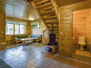A wooden cabin interior with a staircase, a sofa, a table, and a television. - Vuorimaja by Interhome (Ristiina)