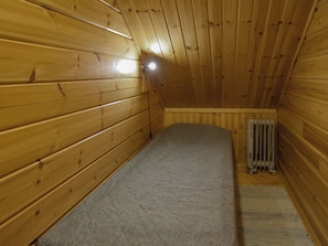 A small, single-bed room with wooden walls and a sloped ceiling. - Vuorimaja by Interhome (Ristiina)