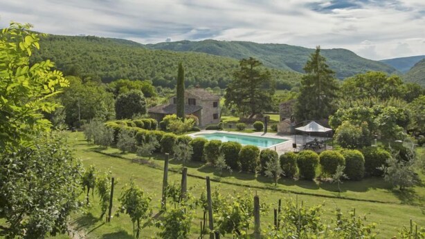 Un paysage verdoyant et luxuriant, avec une piscine, une maison en pierre et un belvédère.