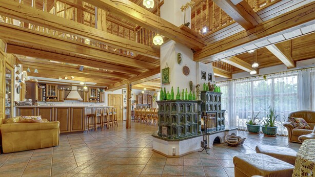 A spacious, high-ceilinged lobby with wooden beams, a central bar area with stools, and a seating area with leather sofas. - Borówna by Interhome (Borowna)