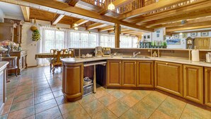 A spacious kitchen with wooden cabinets, a large island, and hanging pendant lights. - Borówna by Interhome (Borowna)