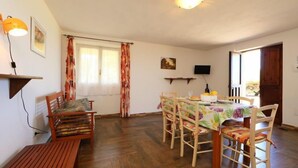 Ein Essbereich mit Holztisch und -stühlen, einer Bank, einem an der Wand montierten Fernseher und einem Fenster mit Vorhängen.