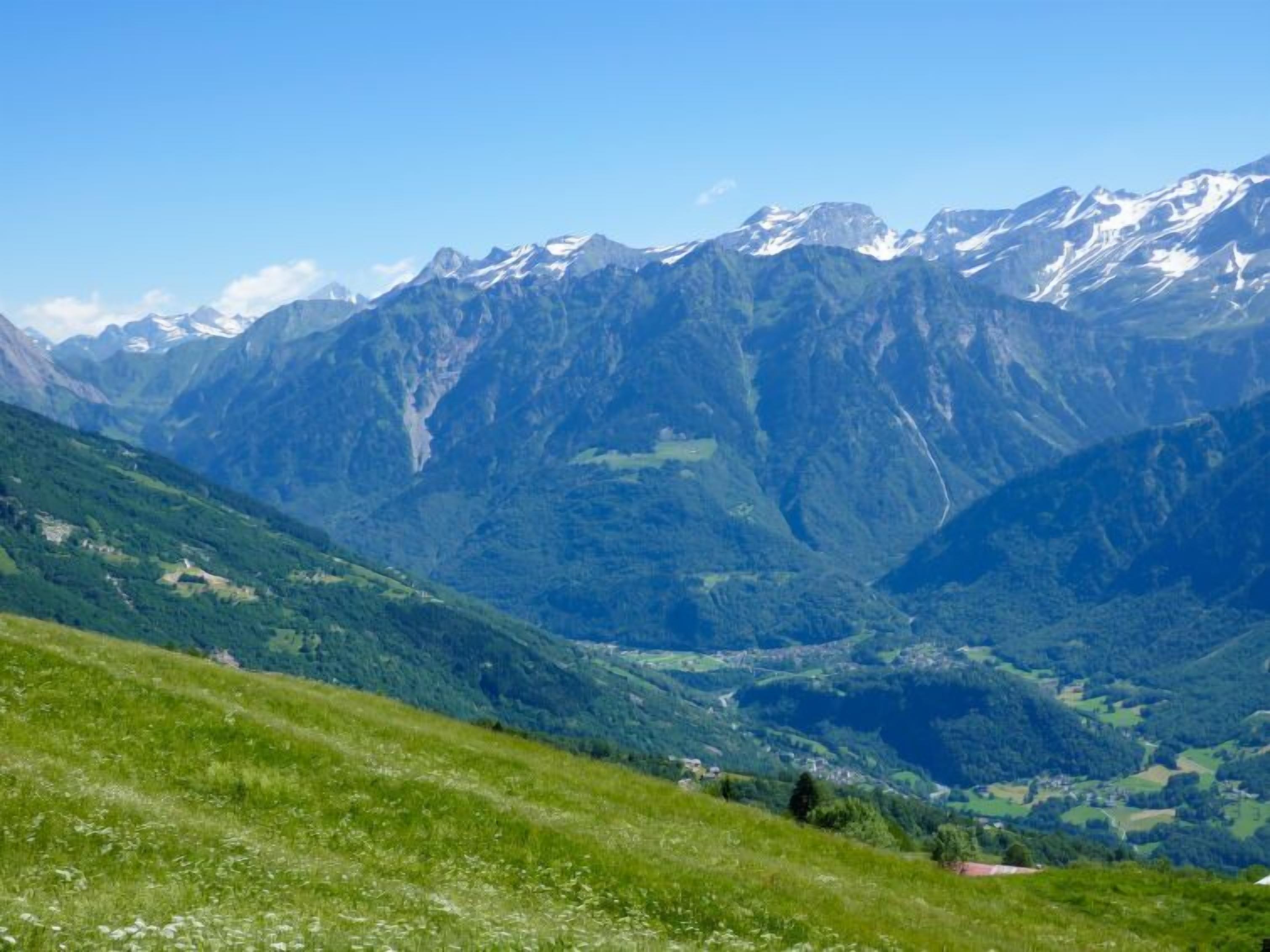 Eine gebirgige Landschaft mit einem Tal und blauem Himmel.