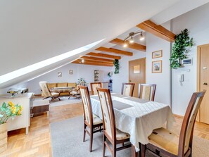 A dining area with a table set for six, wooden chairs, a sofa, and a small side table.