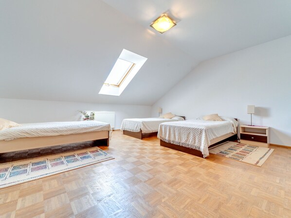 A bedroom with two beds, a skylight, and a wooden floor.