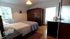 Un dormitorio con una cama, un armario de madera, un escritorio y un radiador.