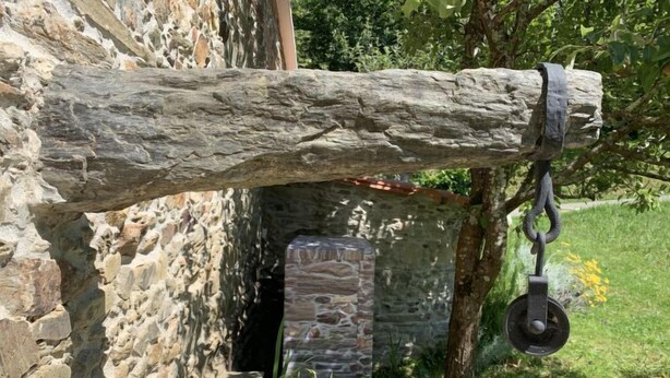 Un muro de piedra rústica con una viga de madera y un sistema de poleas.