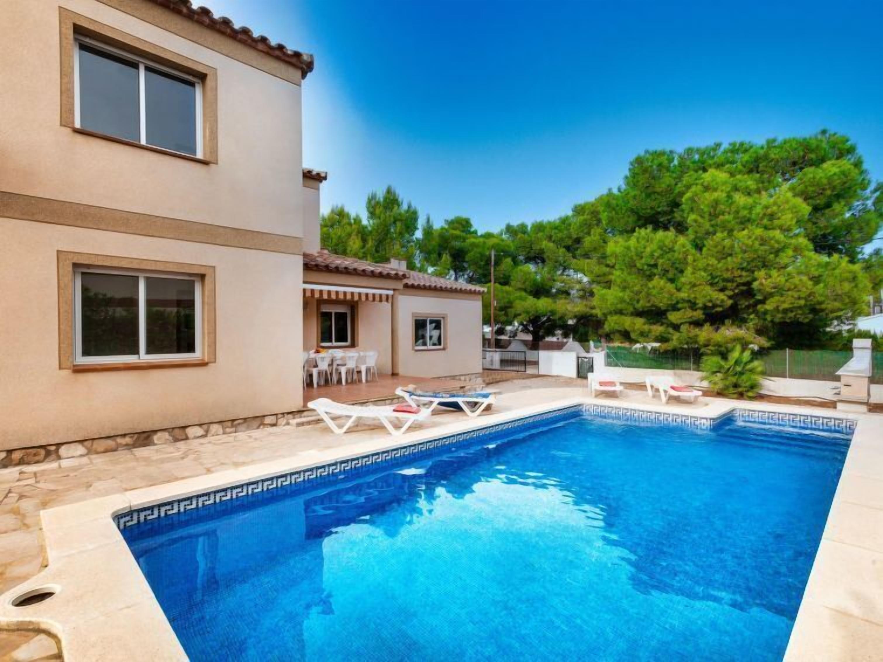 A swimming pool with lounge chairs, a patio area, and a building with windows.
