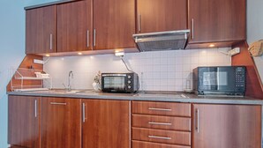 A kitchen with wooden cabinets, a microwave, and a toaster. - Głęboczek 21 by Interhome (Gleboczek)