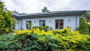 A modern two-story house with a grey exterior, large windows, and a well-maintained garden with various shrubs and trees. - Głęboczek 21 by Interhome (Gleboczek)