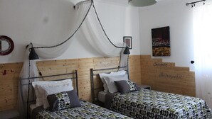 A bedroom with two beds, a wooden headboard, a hanging light fixture, and a wall-mounted artwork.