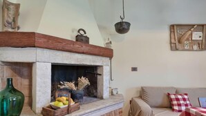 A cozy living room with a stone fireplace, a wooden bench, and a cushioned sofa. - Apartment SaNi by Interhome (Pula)