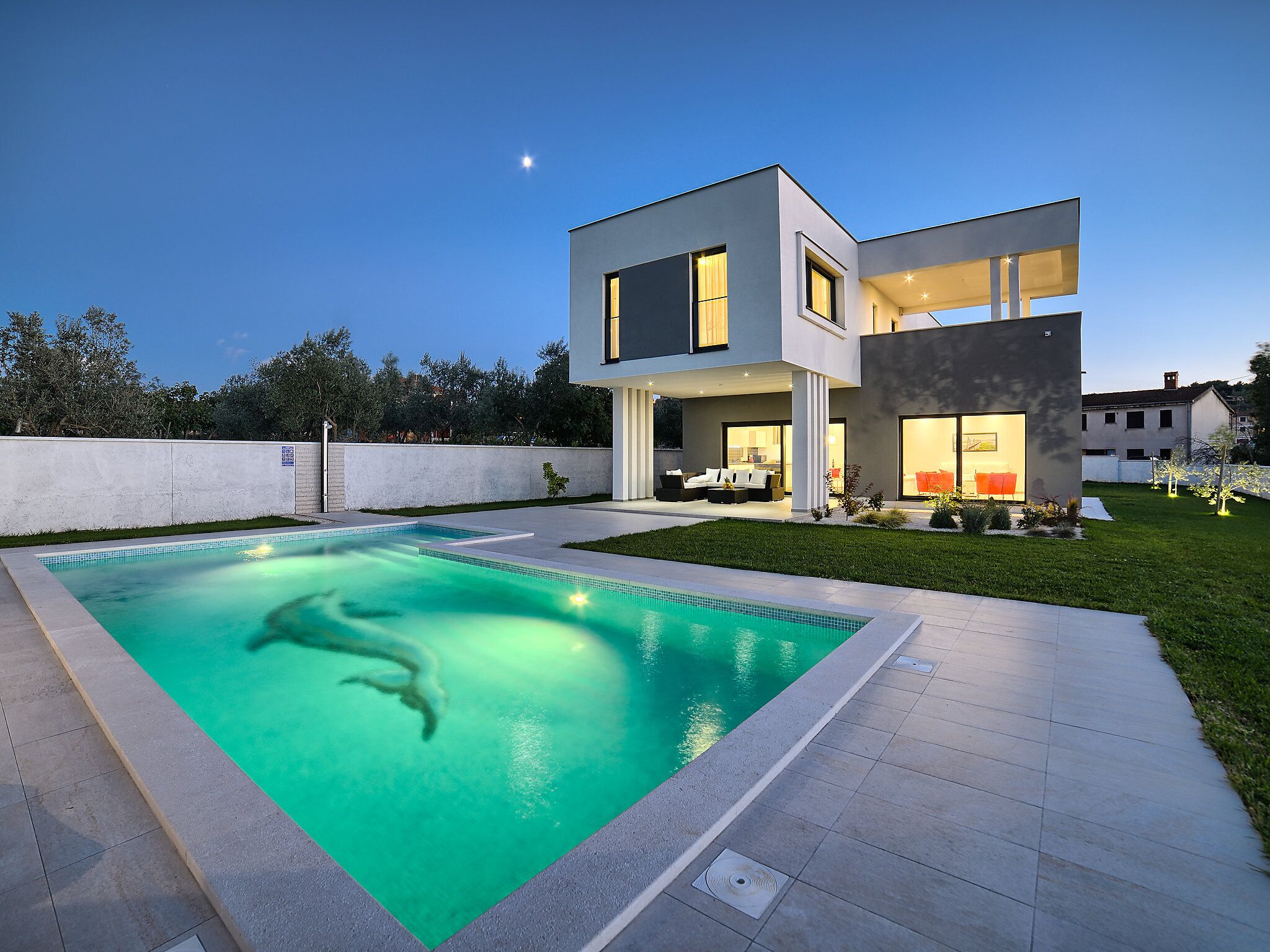 A modern two-story house with a swimming pool, outdoor seating area, and a well-maintained lawn.