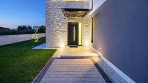 Een modern huis met een stenen gevel, een plat dak en een goed verlichte ingang.