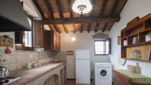 A compact kitchen with a built-in oven, a washing machine, and wooden cabinets. - Ca' di Bacco by Interhome (Cortona)