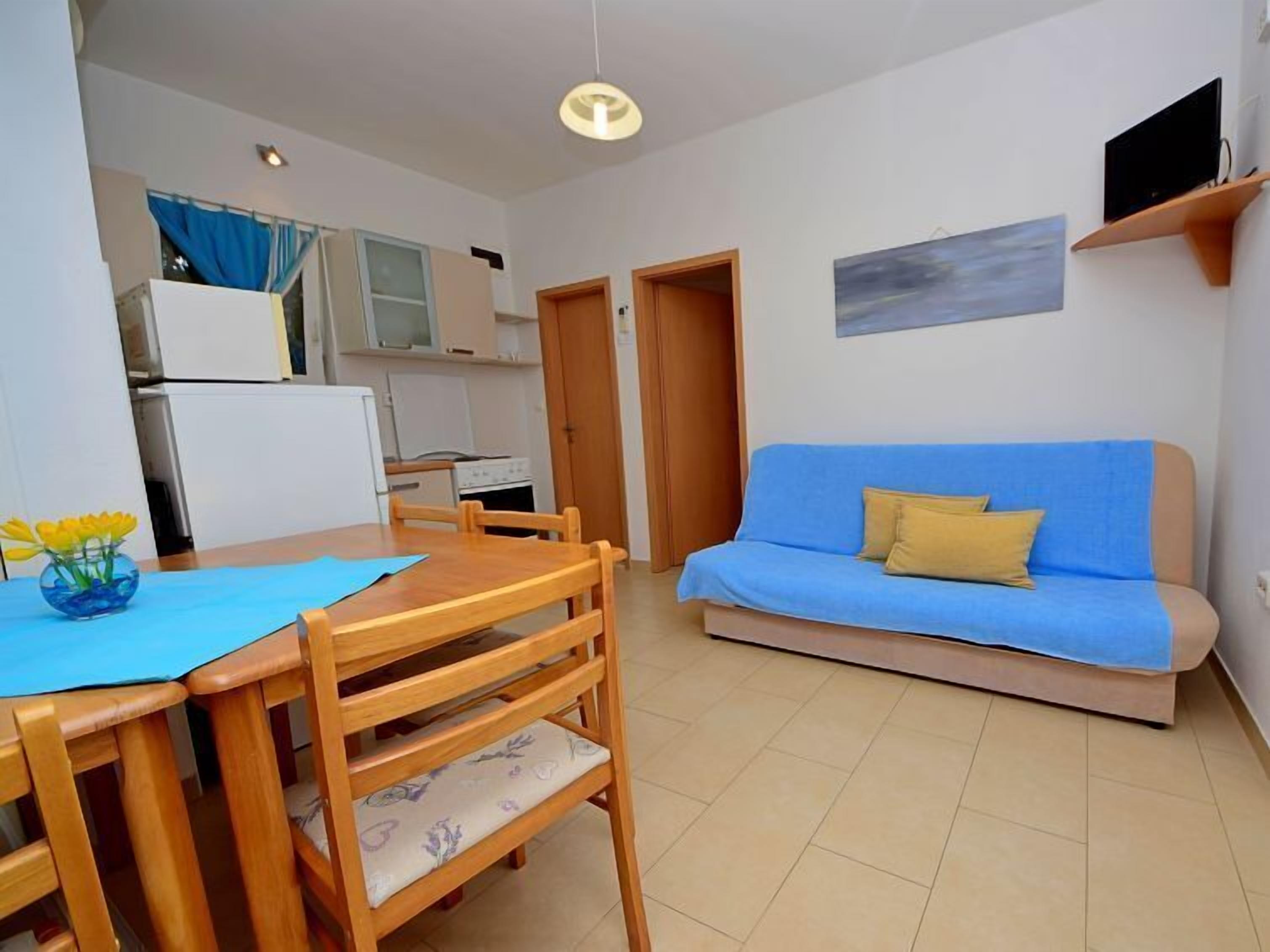A compact living space with a dining area, kitchenette, and a sofa.