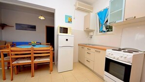 Una cucina compatta con zona pranzo, dotata di frigorifero, piano cottura e forno a microonde.