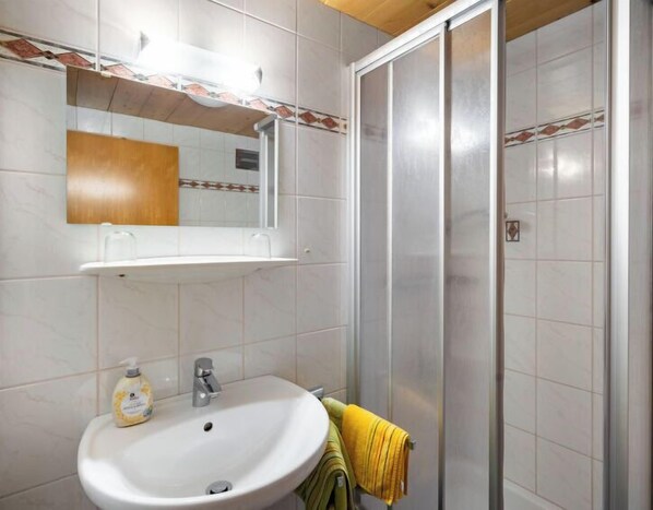 Ein Badezimmer mit Waschbecken, Spiegel und Duschbereich.