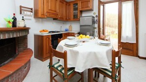 Une cuisine compacte avec des meubles en bois, une cuisinière à gaz et une table à manger pour quatre personnes.