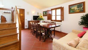 Un coin repas avec une table et des chaises en bois, un téléviseur et un tableau accroché au mur.