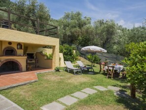 A patio area with a stone pathway, outdoor seating, and a barbecue grill. - Le Bozzelle by Interhome (Massarosa)