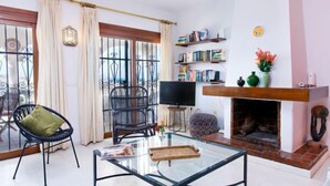 Ein Wohnzimmer mit Glastisch, Fernseher, Kamin und Bücherregal.