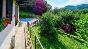 Ein Poolbereich mit einem Kiesweg, umgeben von üppiger Vegetation und einer Bergkulisse.