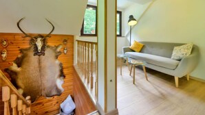 Ein Zimmer mit einer Holzwand, die mit Tierfellen verziert ist, einem grauen Sofa und einem kleinen Tisch.