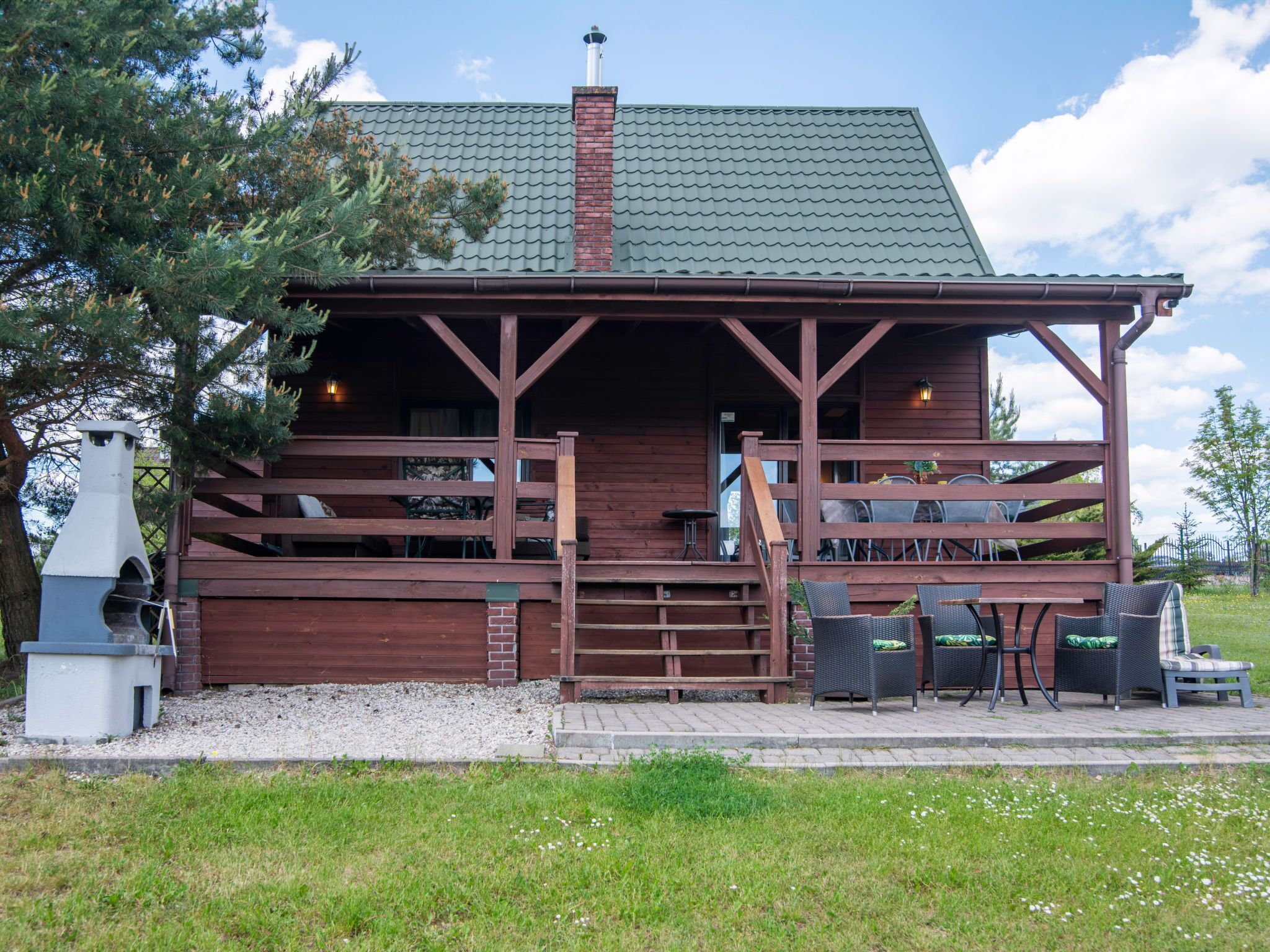 Een rustieke hut met een overdekte veranda, buiten zitplaatsen en een schoorsteen.