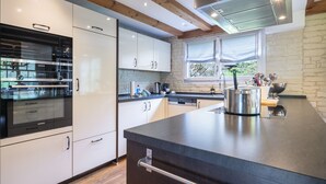 A modern kitchen with a built-in oven, stainless steel appliances, and a large island with a kettle.