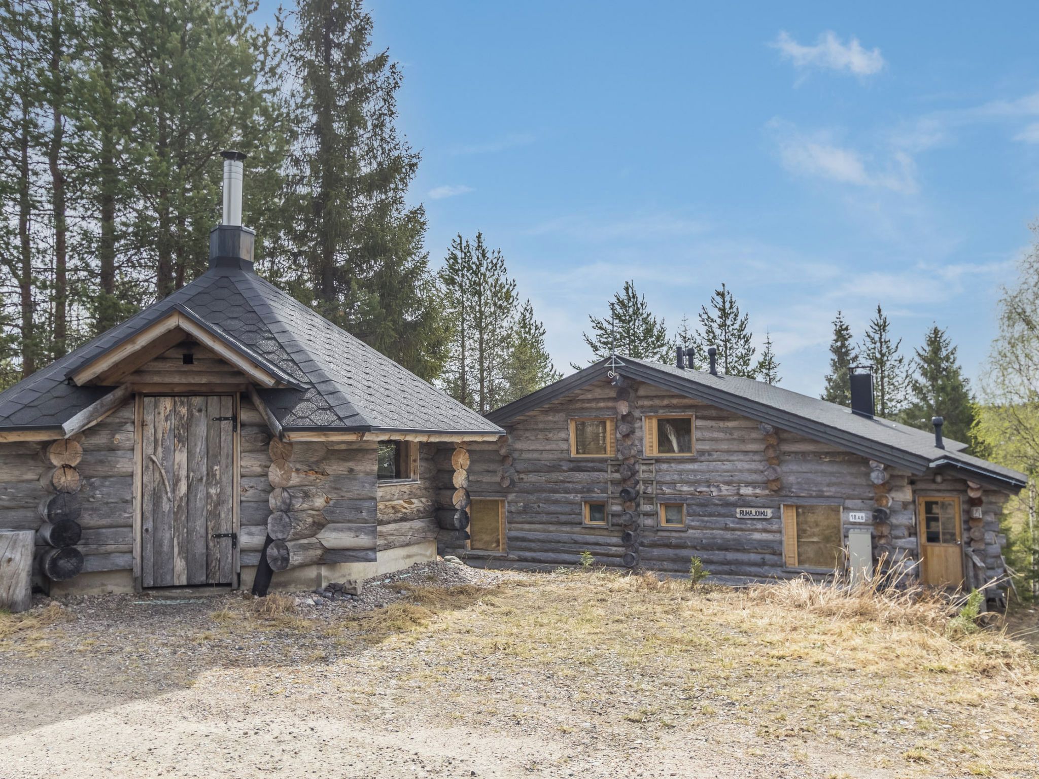 Une cabane rustique en rondins de bois, avec une cheminée, une porte en bois et une fenêtre.