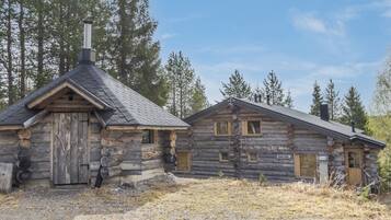 Une cabane rustique en rondins de bois, avec une cheminée, une porte en bois et une fenêtre.