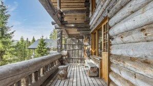 Une cabane en rondins dotée d’une terrasse en bois, d’une balustrade en bois et d’une fenêtre avec une porte en bois.