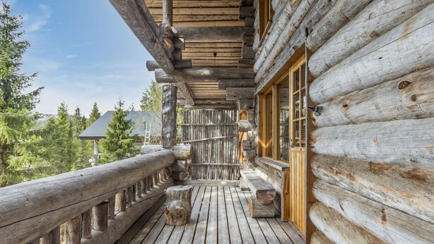 Une cabane en rondins dotée d’une terrasse en bois, d’une balustrade en bois et d’une fenêtre avec une porte en bois.