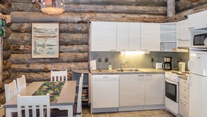 Une cuisine rustique aux murs en bois, avec une table à manger et des chaises, ainsi que des appareils électroménagers modernes.