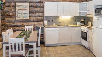 A rustic kitchen with wooden walls, a dining table with chairs, and modern appliances.