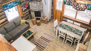 Un intérieur de chalet chaleureux avec une cheminée en pierre, un téléviseur, une table à manger avec des chaises et un canapé.