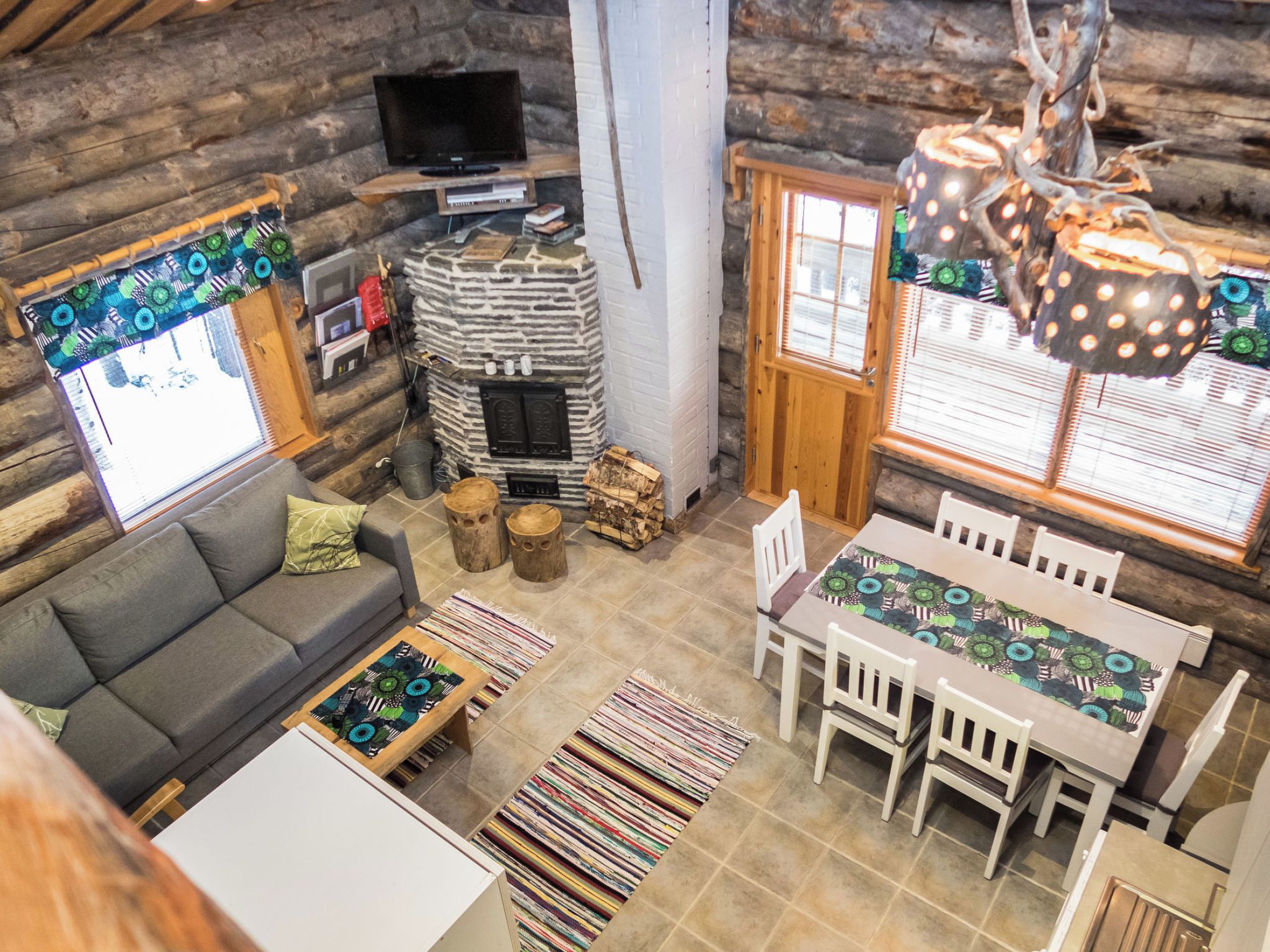 Ein gemütliches Blockhaus-Interieur mit einer Couch, einem Esstisch und einem Kamin.