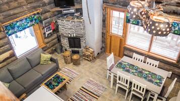 Ein gemütliches Blockhaus-Interieur mit einer Couch, einem Esstisch und einem Kamin.