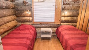 Une chambre de style rustique avec deux lits, un plancher en bois et une petite table.