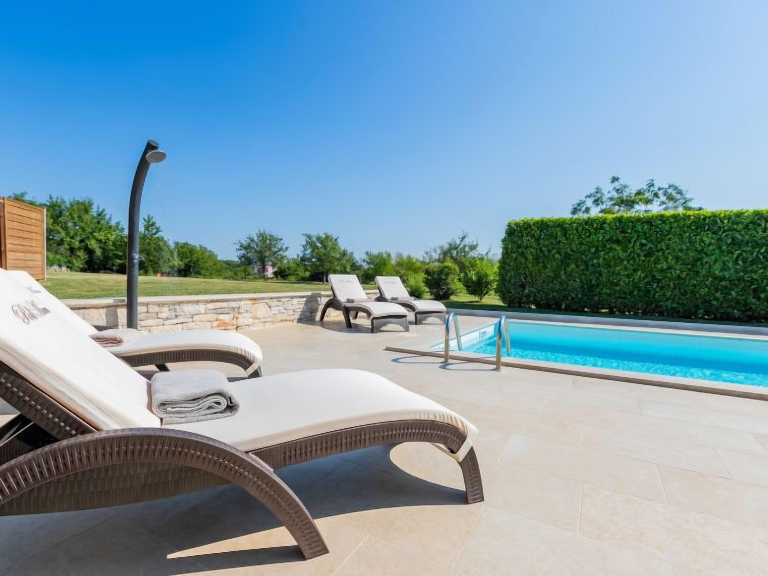 Zona de piscina con sillones de descanso y una pared de piedra.