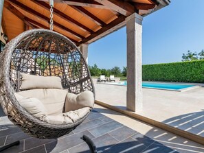 A hanging chair with cushions, a swimming pool, and a covered patio area. - Poli Murvu by Interhome (Sveti Petar u Šumi)