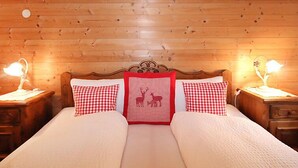 A wooden-paneled room with a bed, two bedside tables, and two lamps.