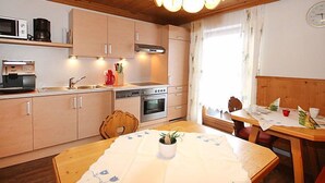 A cozy kitchen with wooden cabinets, a stove, and a dining area with a table set for two.