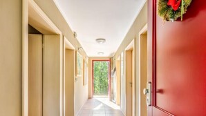 A hallway with beige walls and a red door at the end.