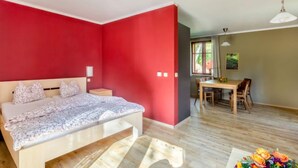 A bedroom with a bed, bedside table, and a dining area with a table and chairs.